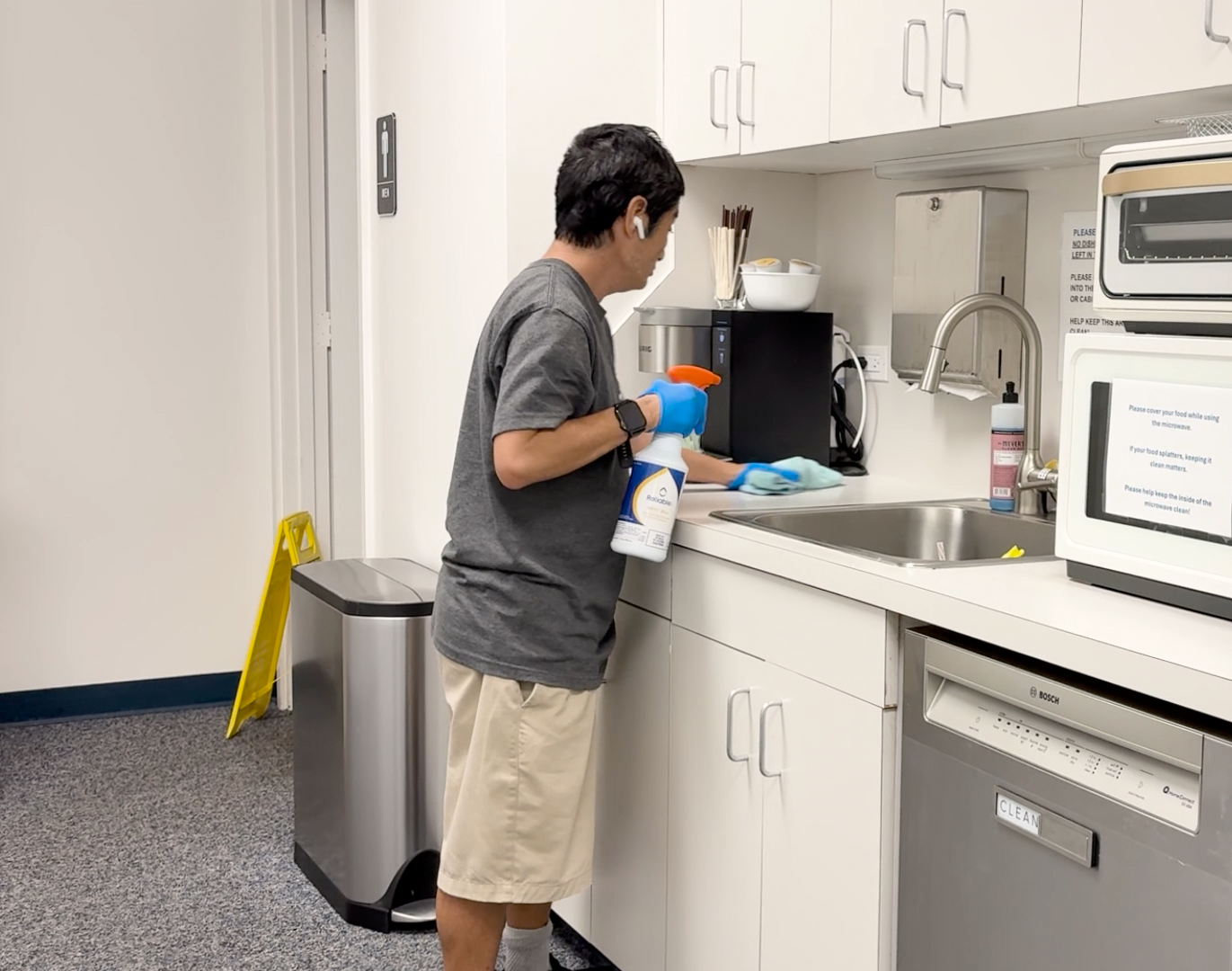 An individual wiping down a kitchenette